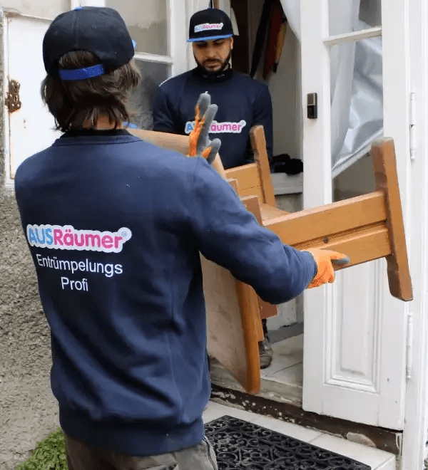 AUSRäumer Team bei der Entrümpelung in Wien – Mitarbeiter trägt einen Holzstuhl aus der Wohnung